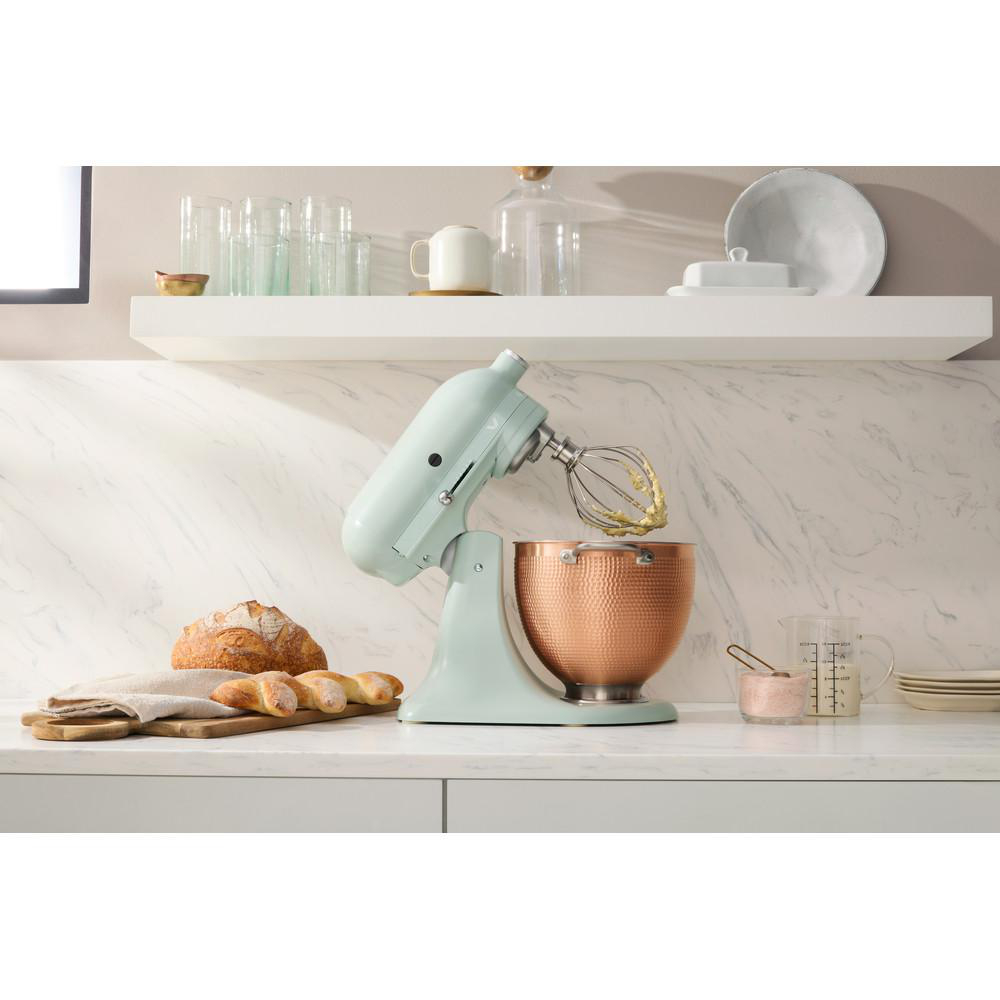 KitchenAid-Mixer mit Kupferkessel und Zutaten auf weißer Arbeitsplatte. Weißer Hintergrund.