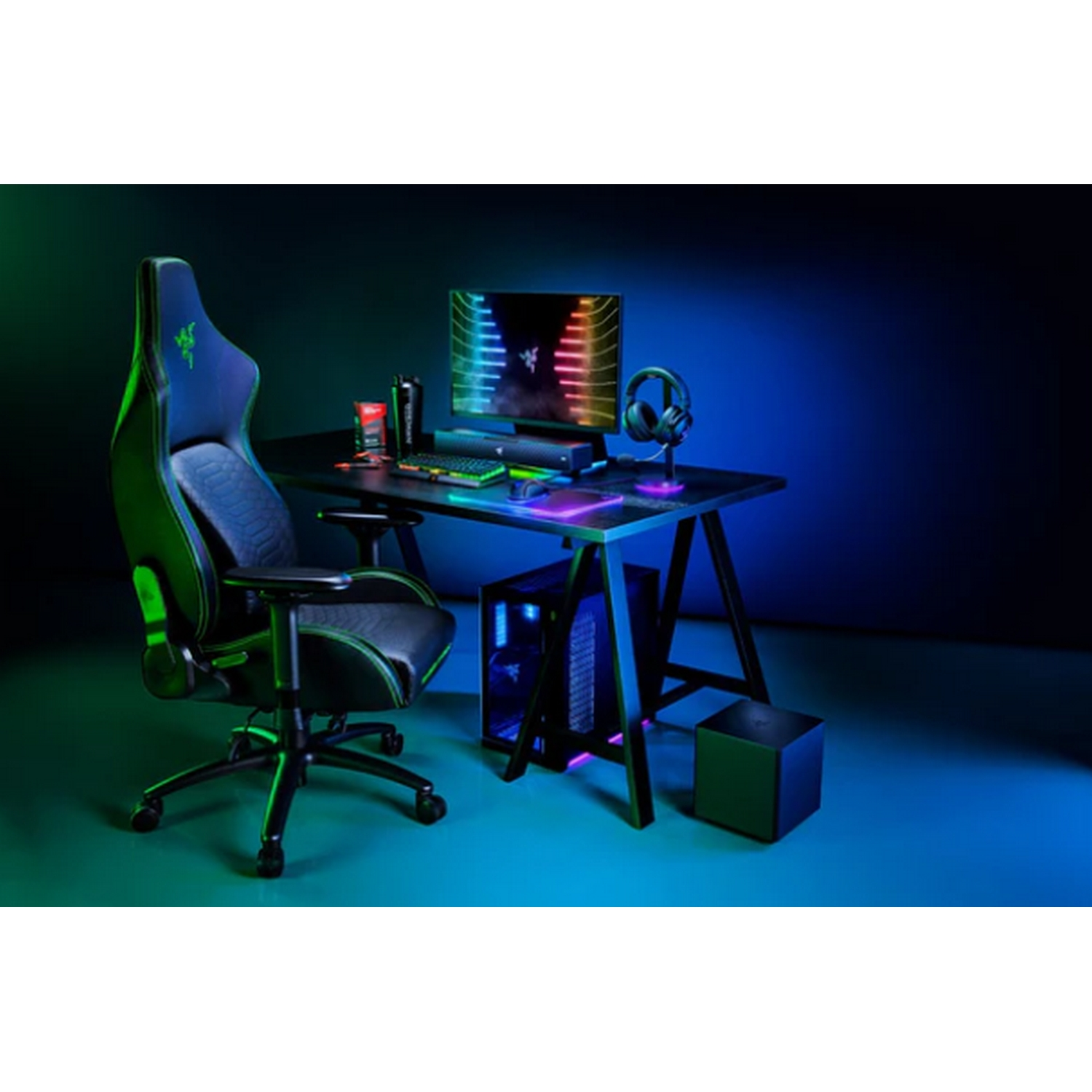 Una configuración de juego con escritorio negro, silla, monitor y PC con luces verdes y azules.