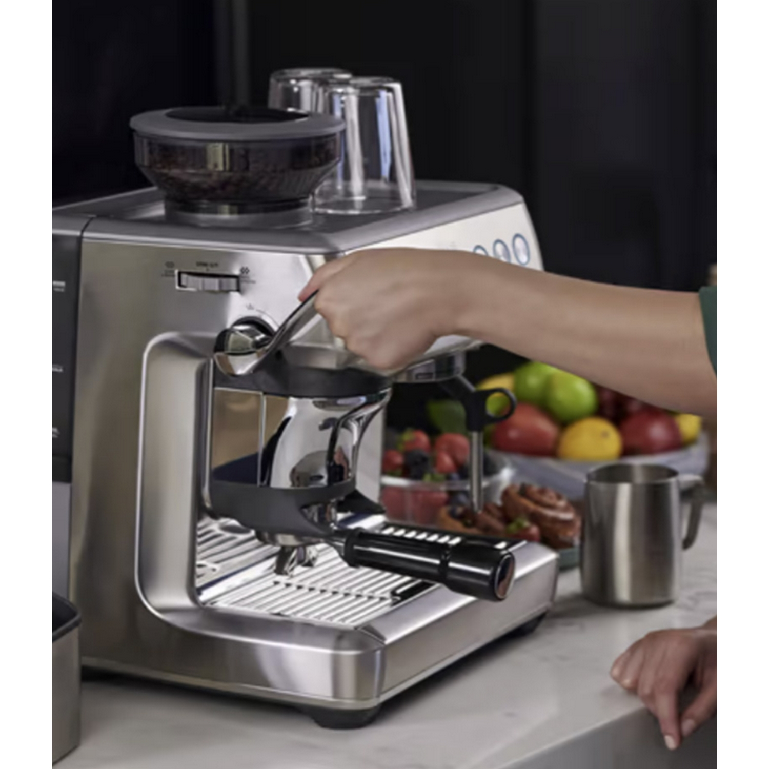 Máquina de espresso plateada con una mano preparando espresso.