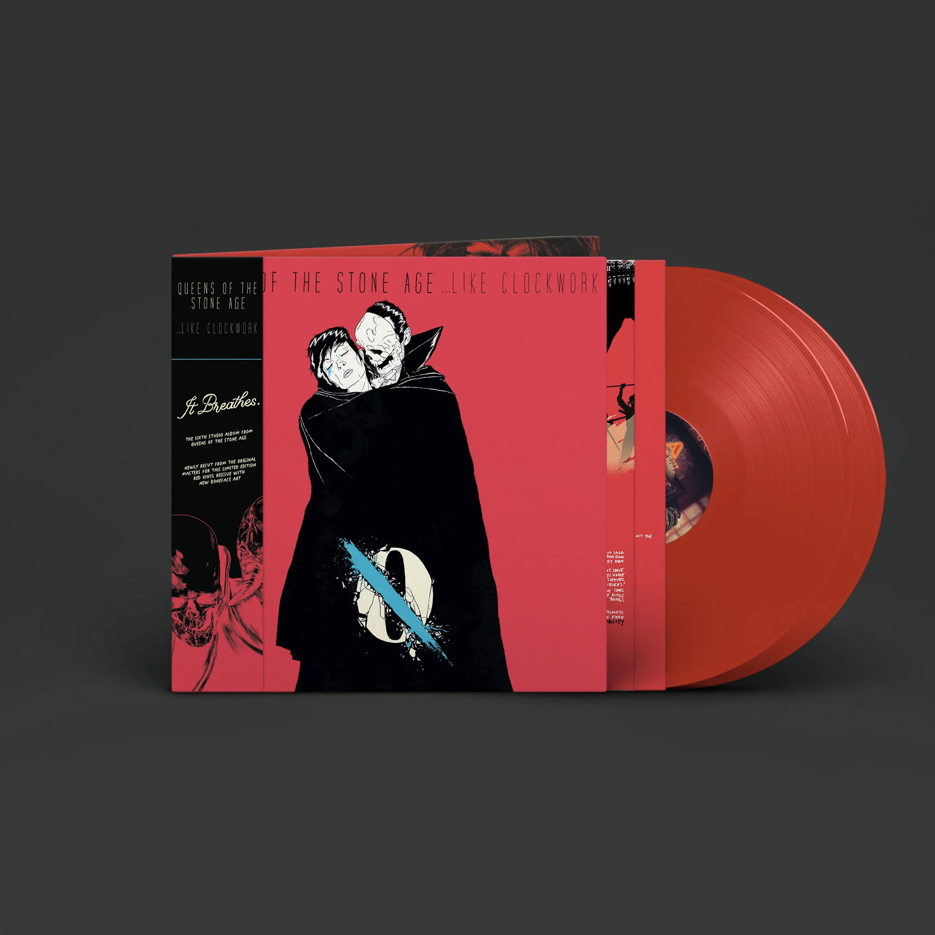 Queens of the Stone Age albumhoes en rode vinylplaat op donkere achtergrond.