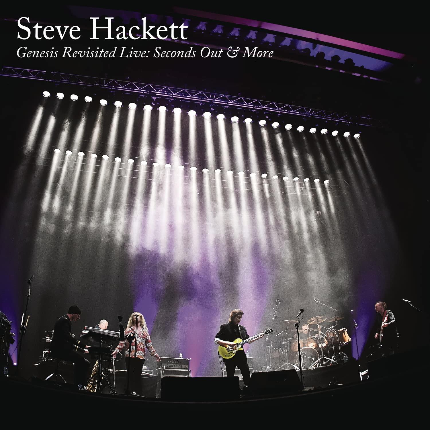 Steve Hackett zenekarja élőben játszik reflektorokkal és lila füsttel.