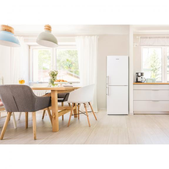 Lichte kamer met een witte koelkast en een keukentafel.