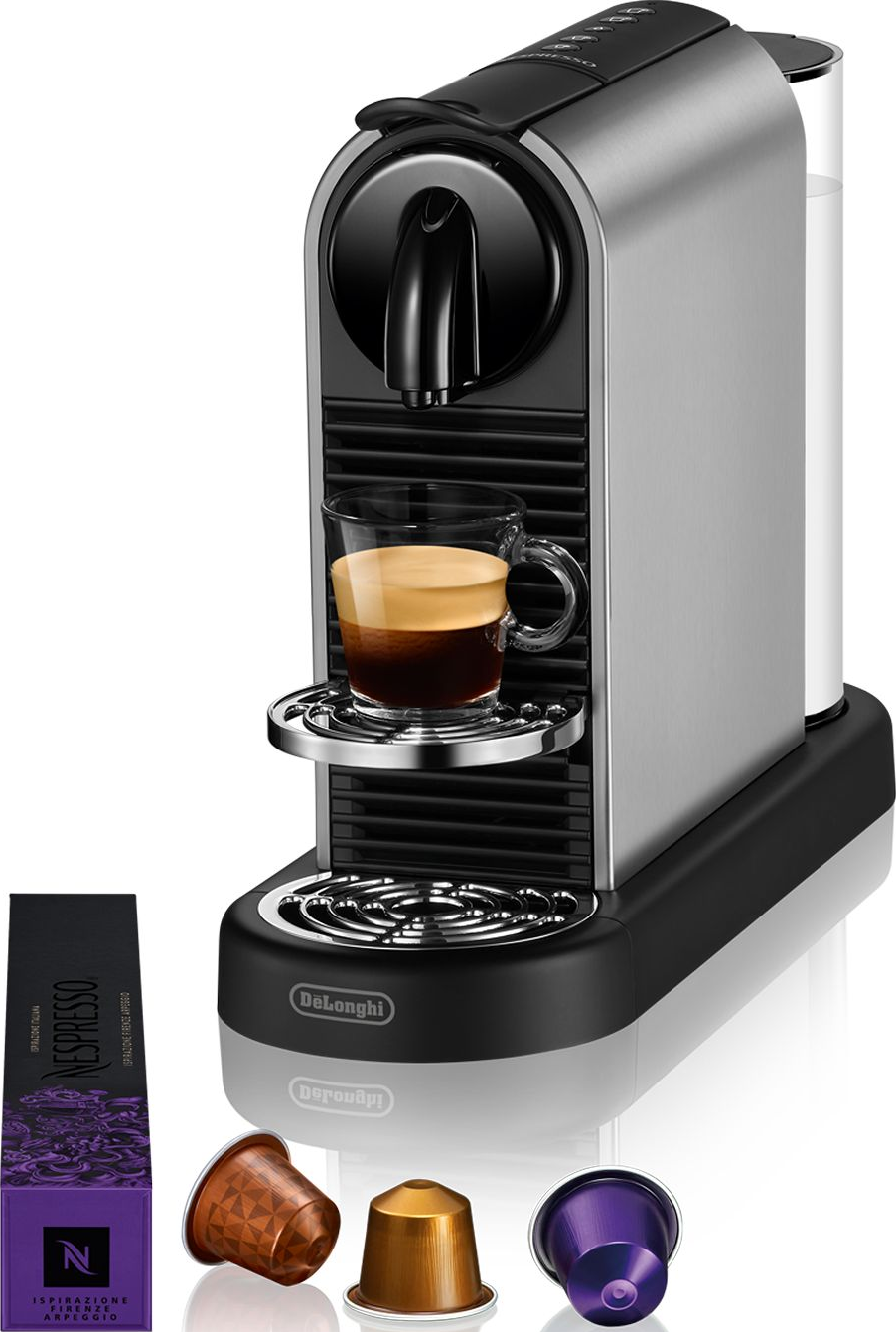 Silber-schwarze Nespresso-Maschine mit Kaffeeglas und Kapseln. Weißer Hintergrund.