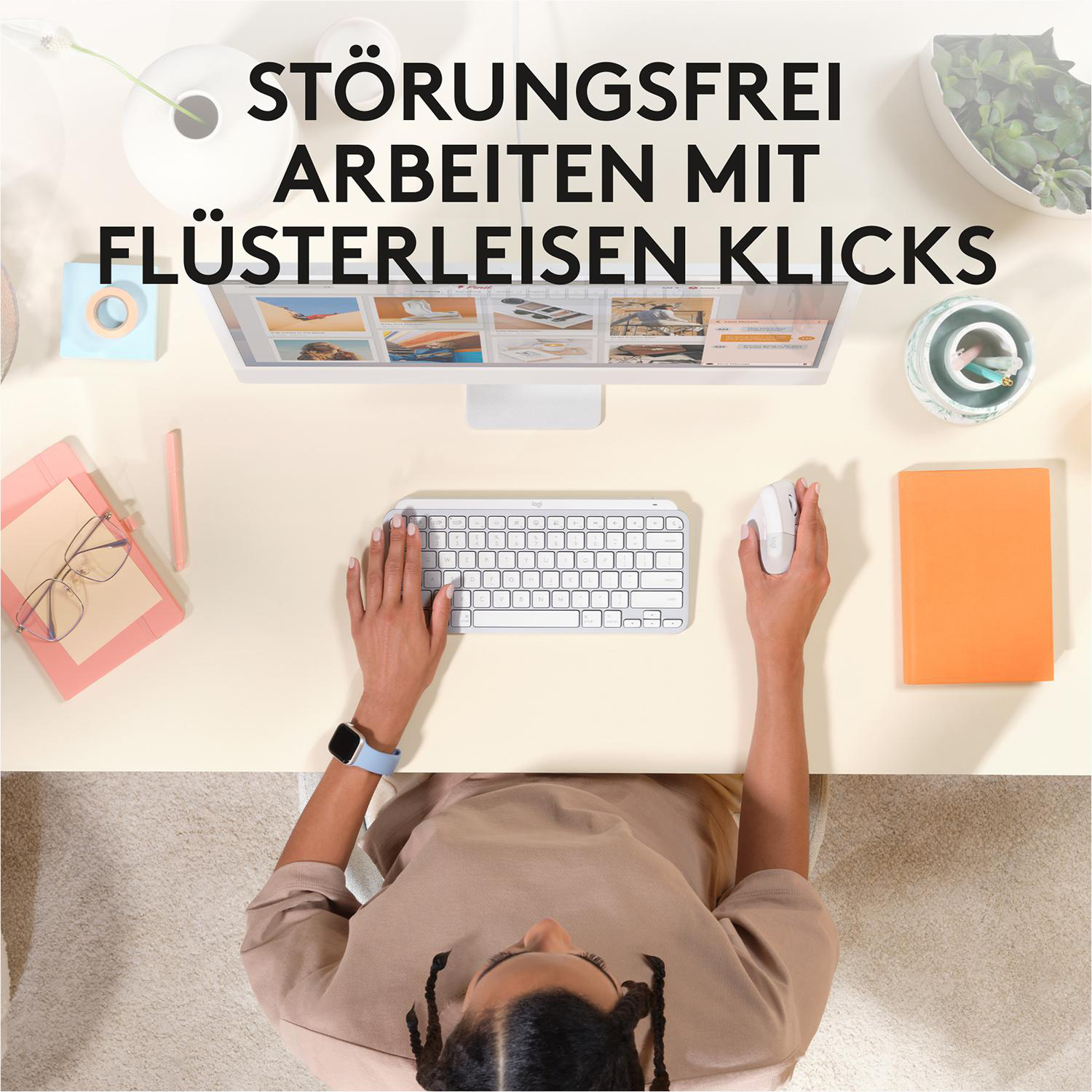 Draufsicht auf einen Schreibtisch mit Tastatur, Maus, Händen einer Frau und Notizbuch.