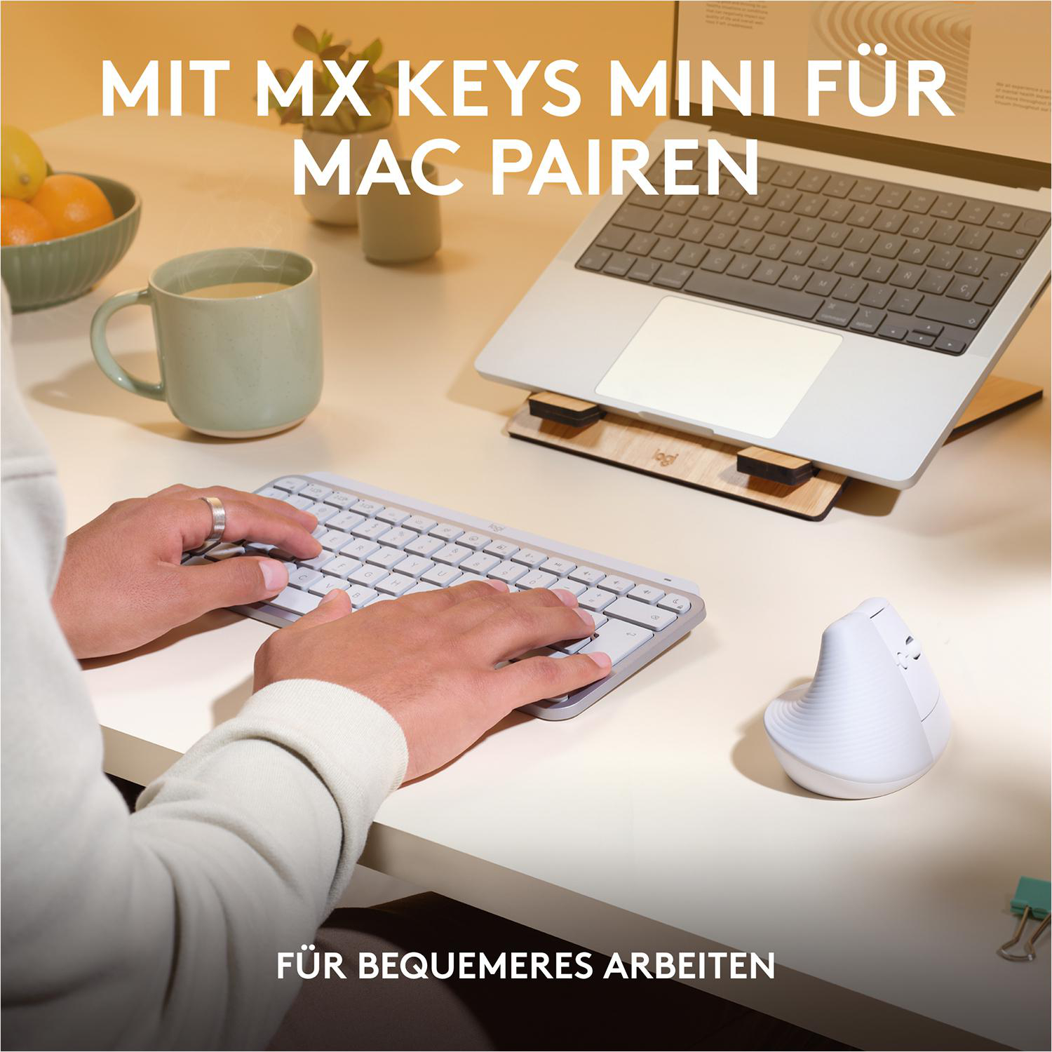 Hände benutzen eine Tastatur und eine Maus, mit einem Laptop und einer Tasse auf einem Schreibtisch.