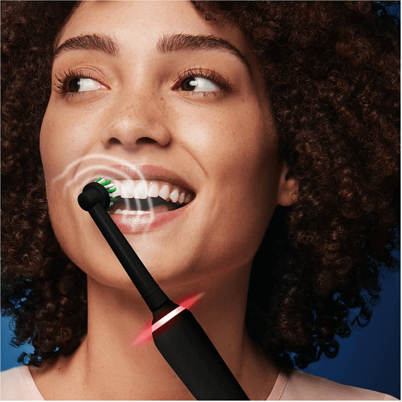 Femme se brossant les dents avec une brosse à dents électrique noire, gros plan.