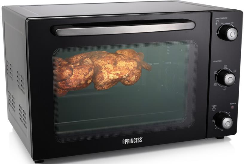 Four noir avec poulet rôti à l'intérieur, fond noir.