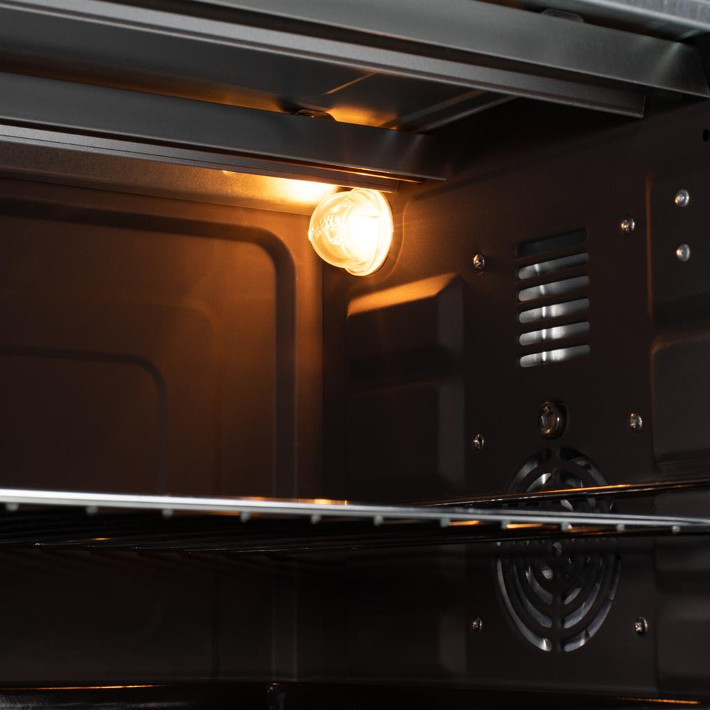 Intérieur du four avec la lumière allumée. Intérieur sombre avec une grille métallique.