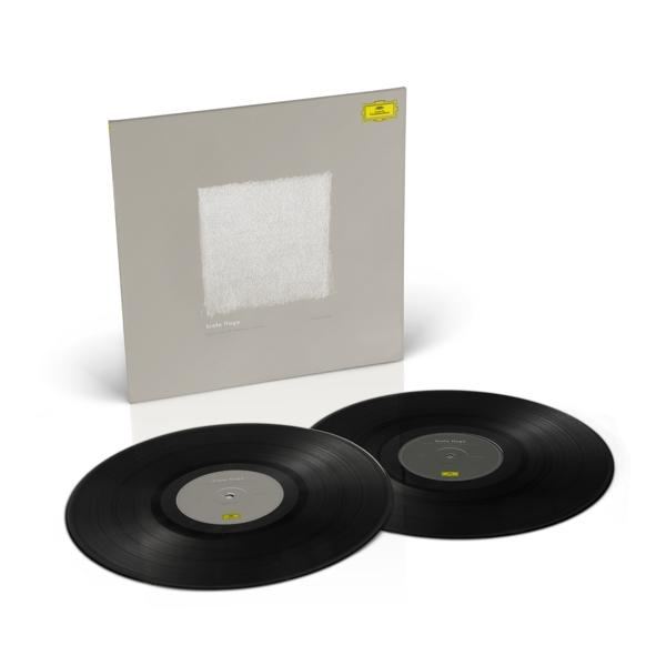 Zwei schwarze Schallplatten und ein graues Albumcover auf weißem Grund.