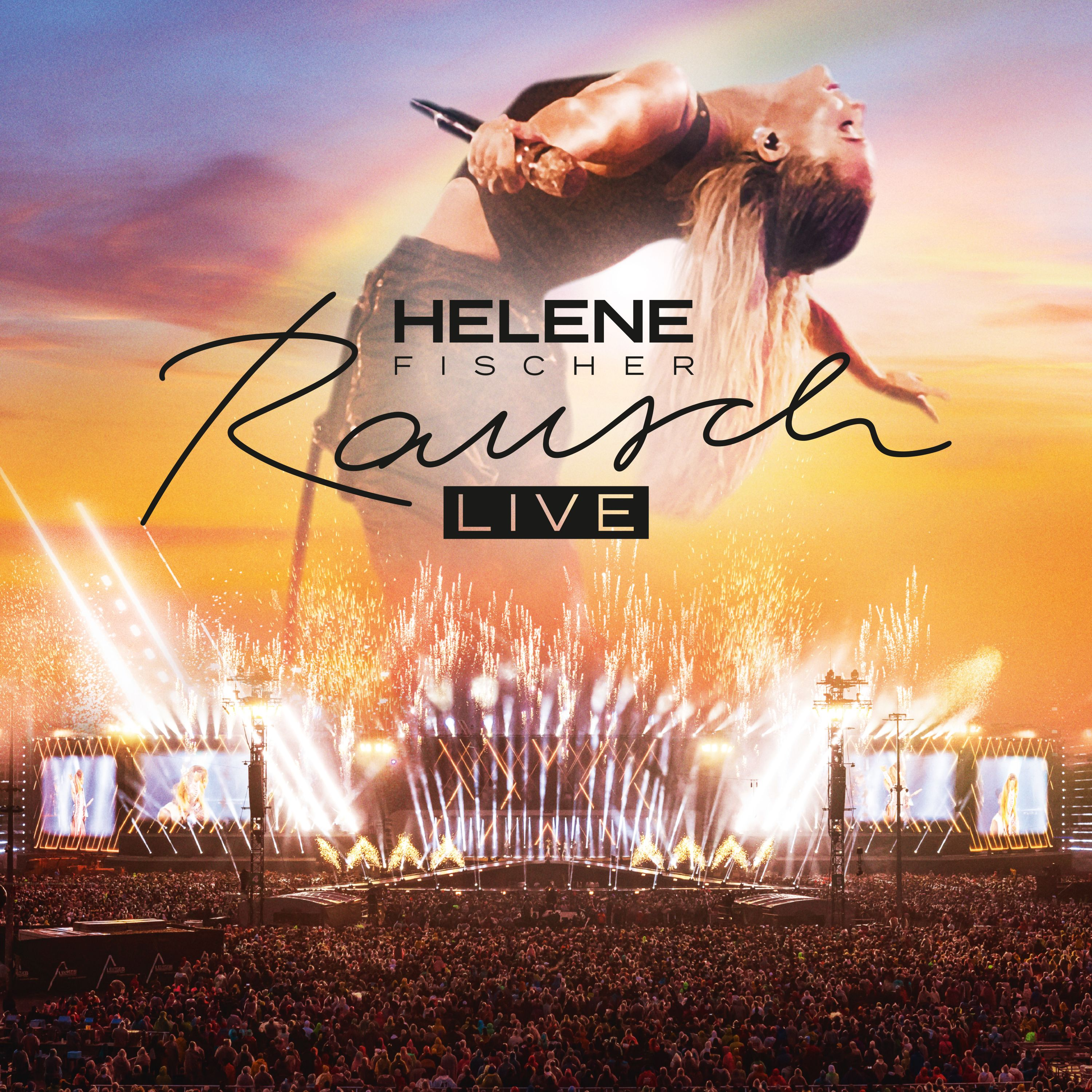 Helene Fischer live auf der Bühne, mit Feuerwerk, Publikum und Bühnenbeleuchtung bei Sonnenuntergang.