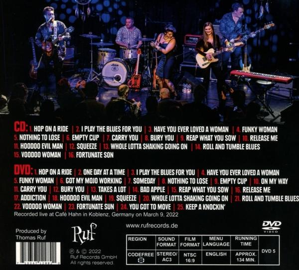 Rückseite einer DVD-Hülle mit Titellisten und Credits. Enthält Bandmitglieder und ein Live-Konzertbild.