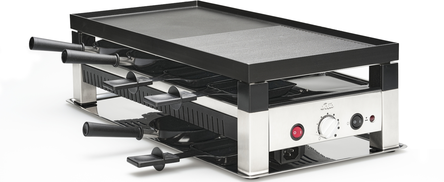 Een zilveren en zwarte raclette grill. Drie niveaus voor pannetjes en een bovenste grilloppervlak. Witte achtergrond.