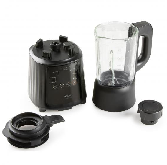 Black blender with a glass jar, and extra parts. The jar is on the right side. All objects are on a white surface.