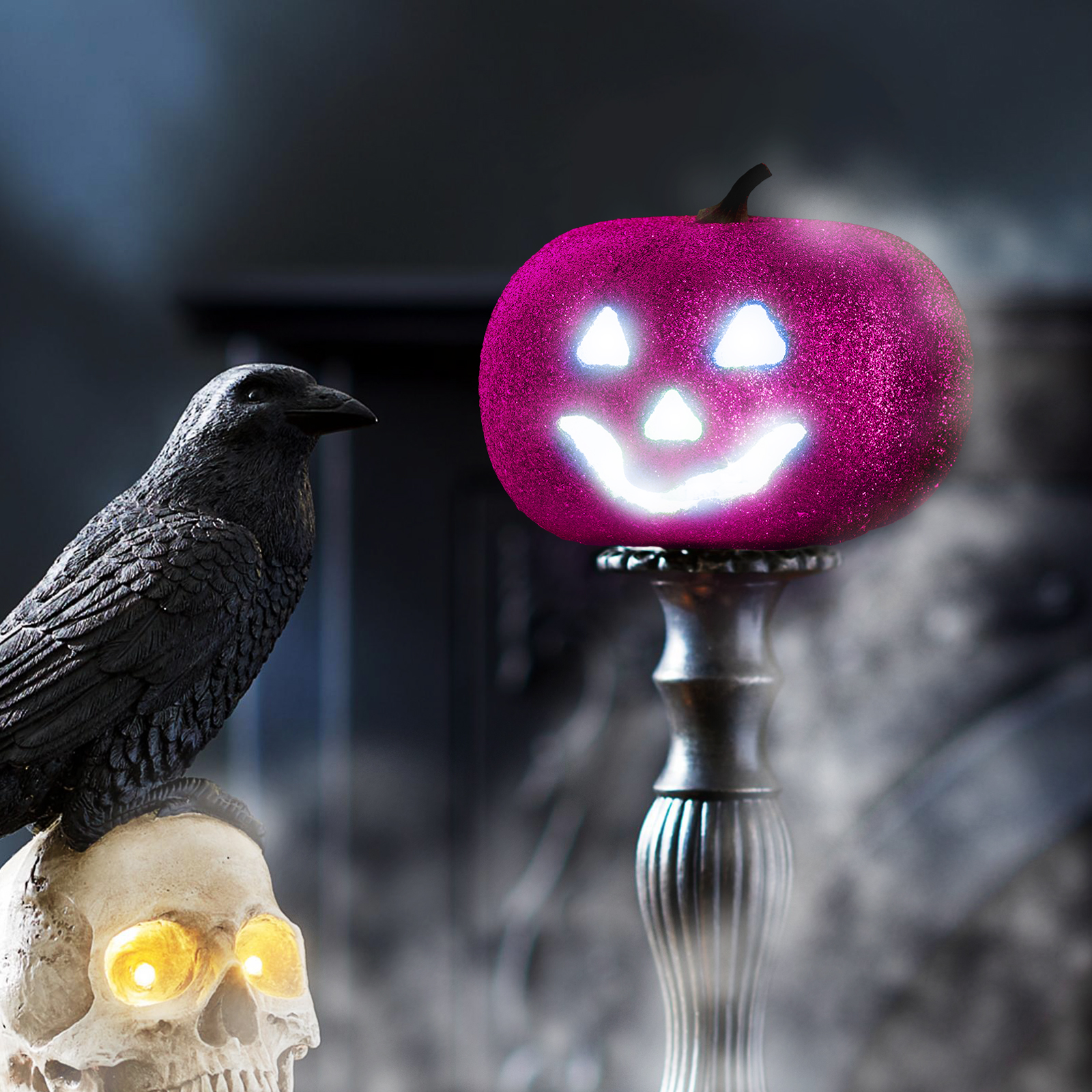 Halloween jelenet egy világító rózsaszín tökkel, koponyával és hollóval, füst a háttérben.