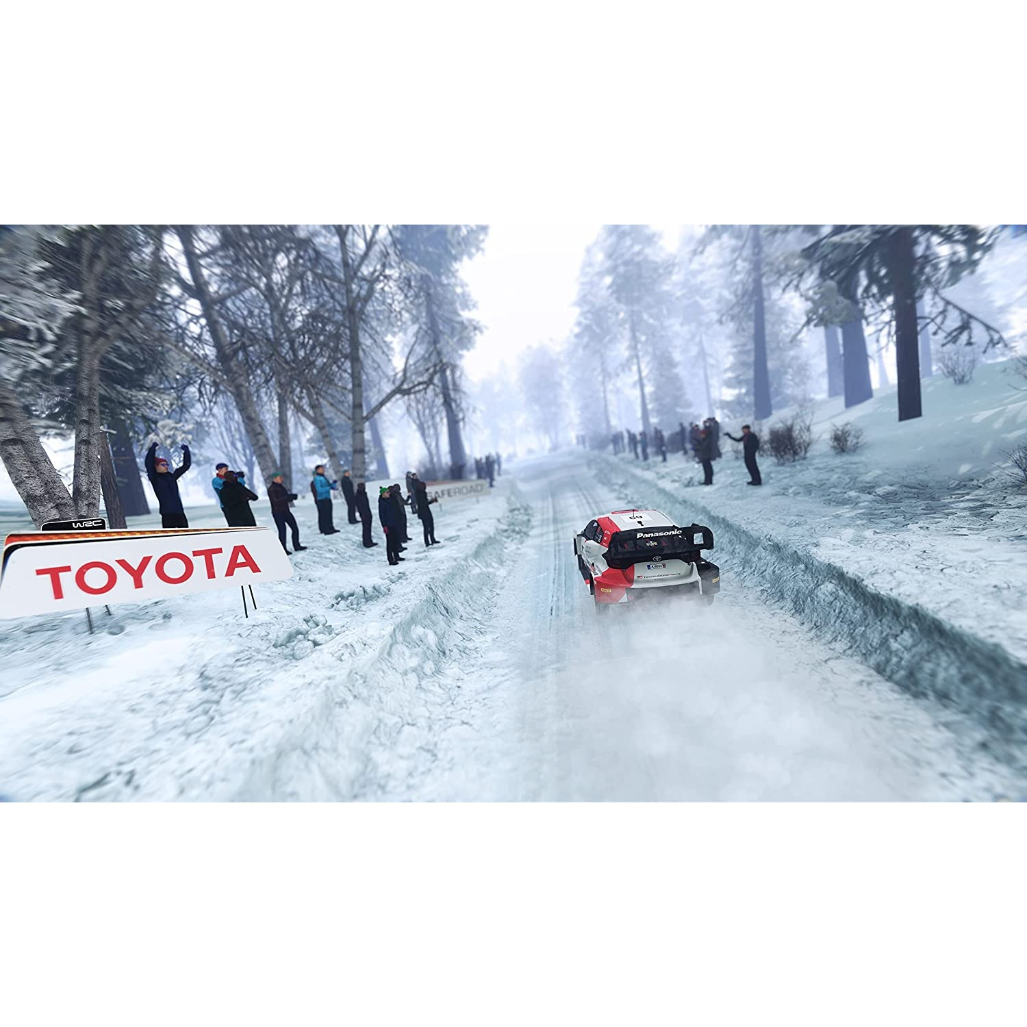 Un coche de rally compite en una pista nevada. Espectadores detrás de barreras. Señal de Toyota.