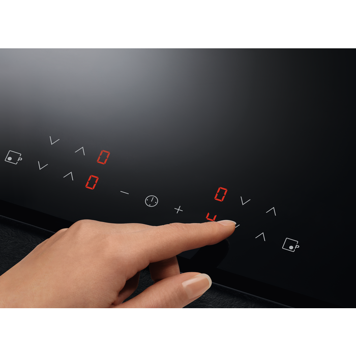 Una mano tocando una placa de inducción negra, mostrando el panel de control.