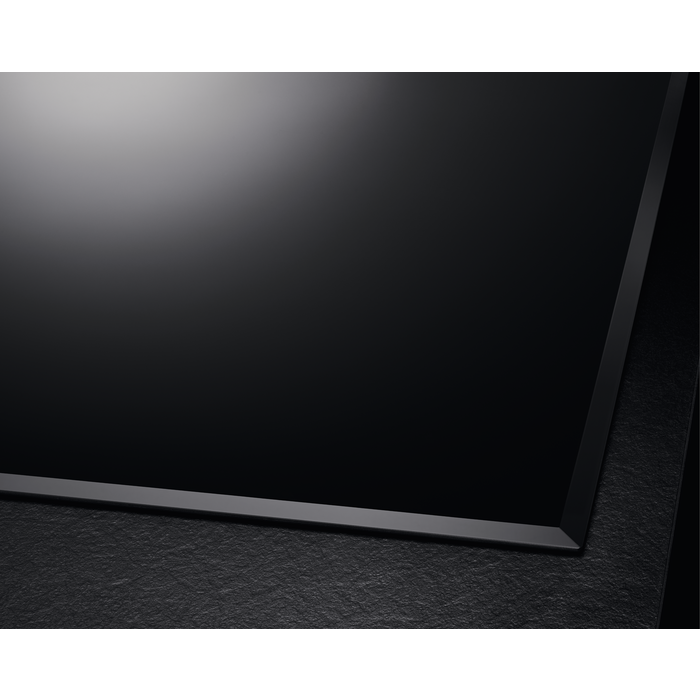 Placa de cocción de vidrio negro con superficie oscura y texturizada y marco negro.
