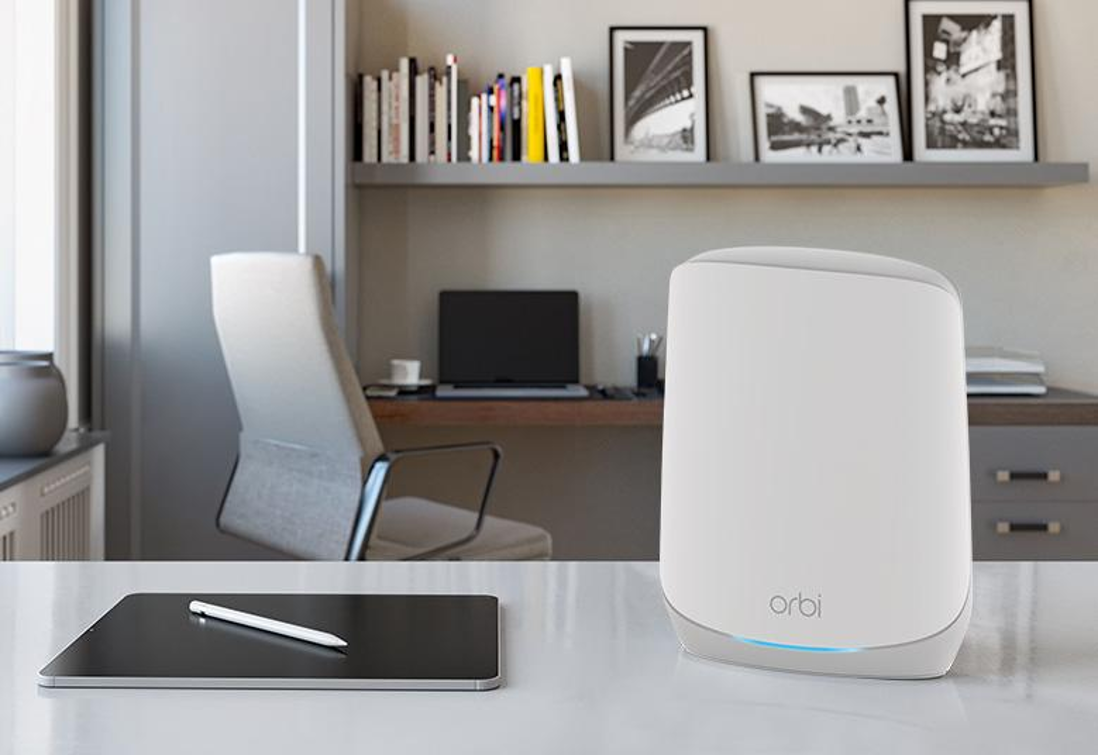 Weißer Router auf einem Schreibtisch mit Tablet und Stift, verschwommener Büro-Hintergrund.