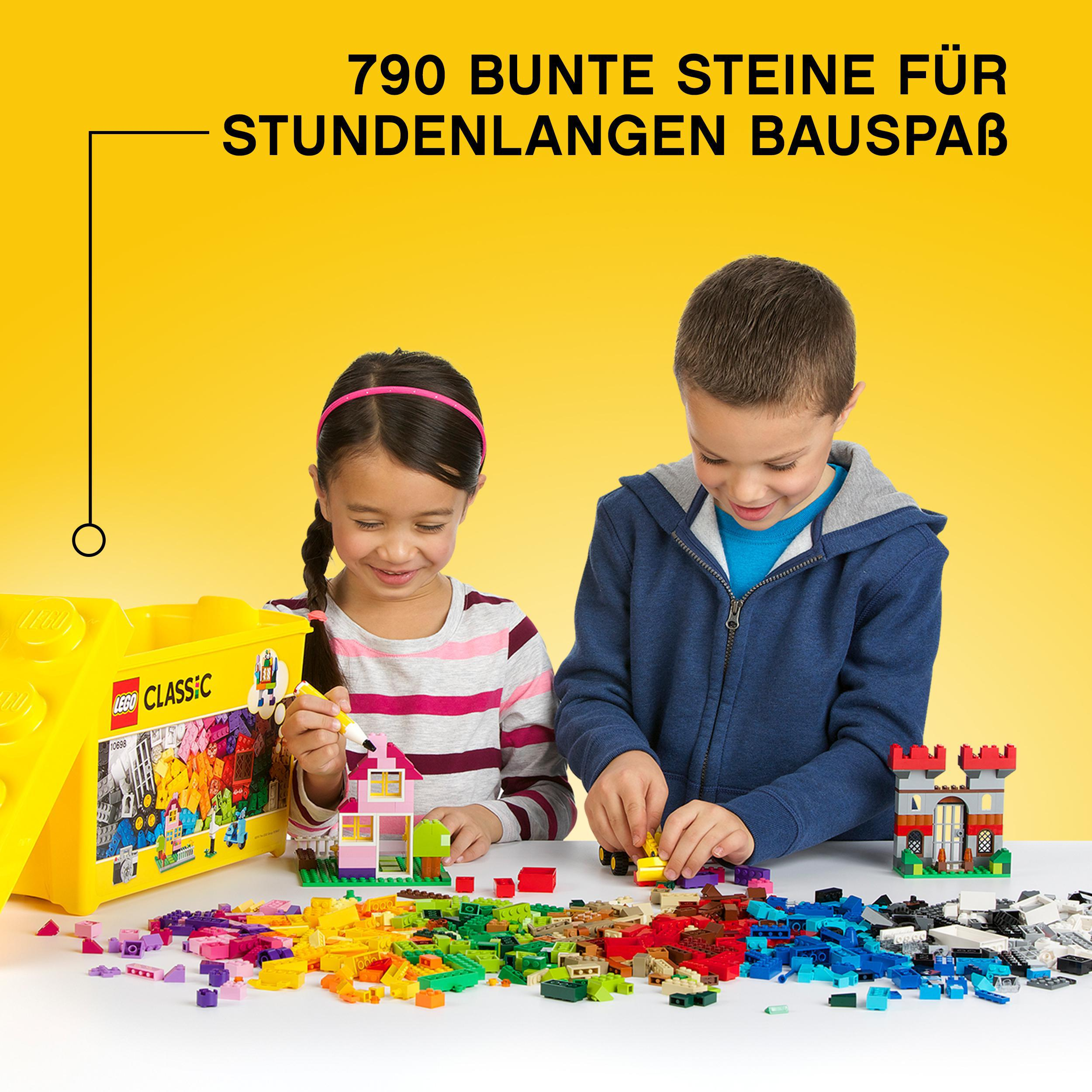 Zwei Kinder bauen mit bunten Legos. Eine Lego-Box steht links.