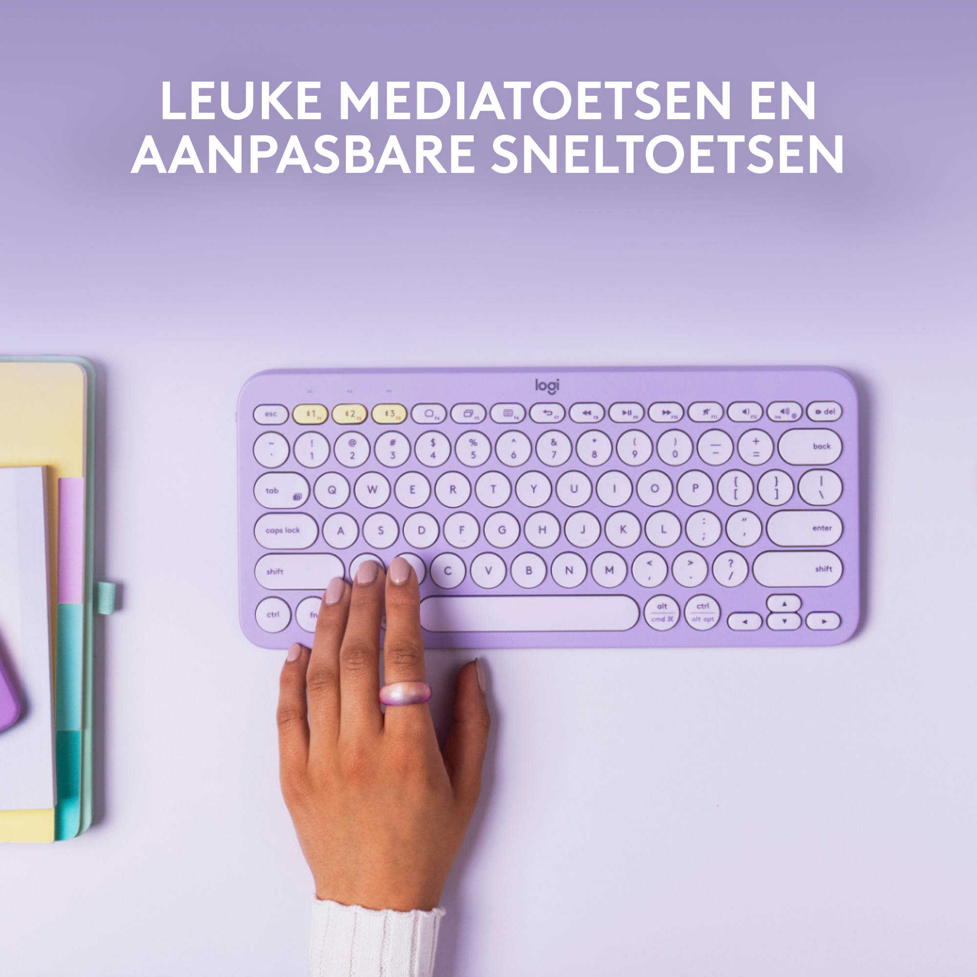 Een lila toetsenbord op een wit oppervlak. Een hand met een ring zweeft boven de toetsen.