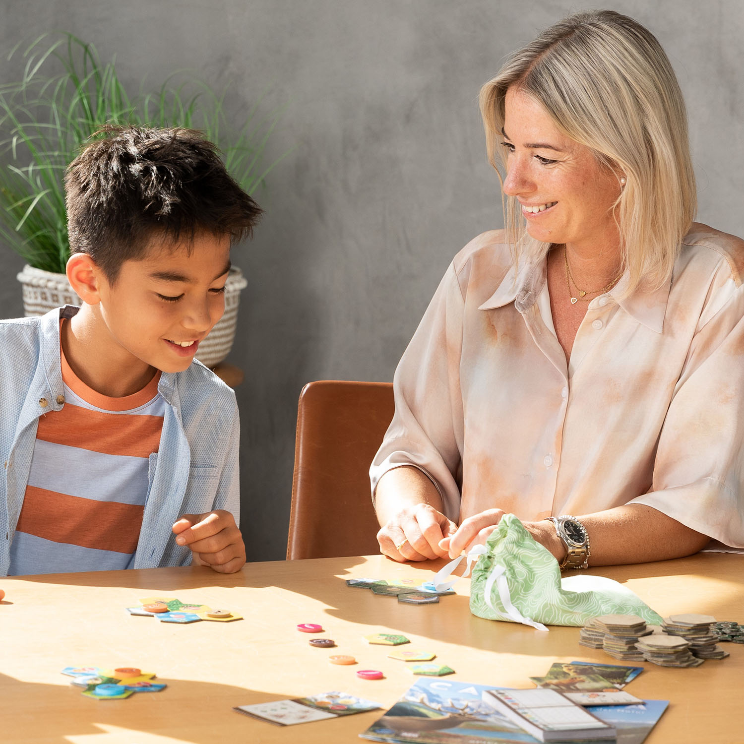 Eine Frau und ein Junge spielen ein Brettspiel am Tisch.