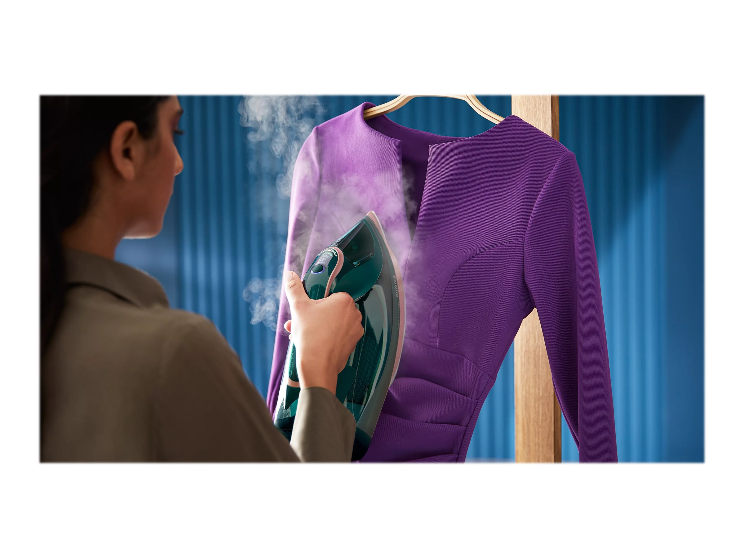 Person bügelt eine lila Jacke an einem Kleiderbügel.