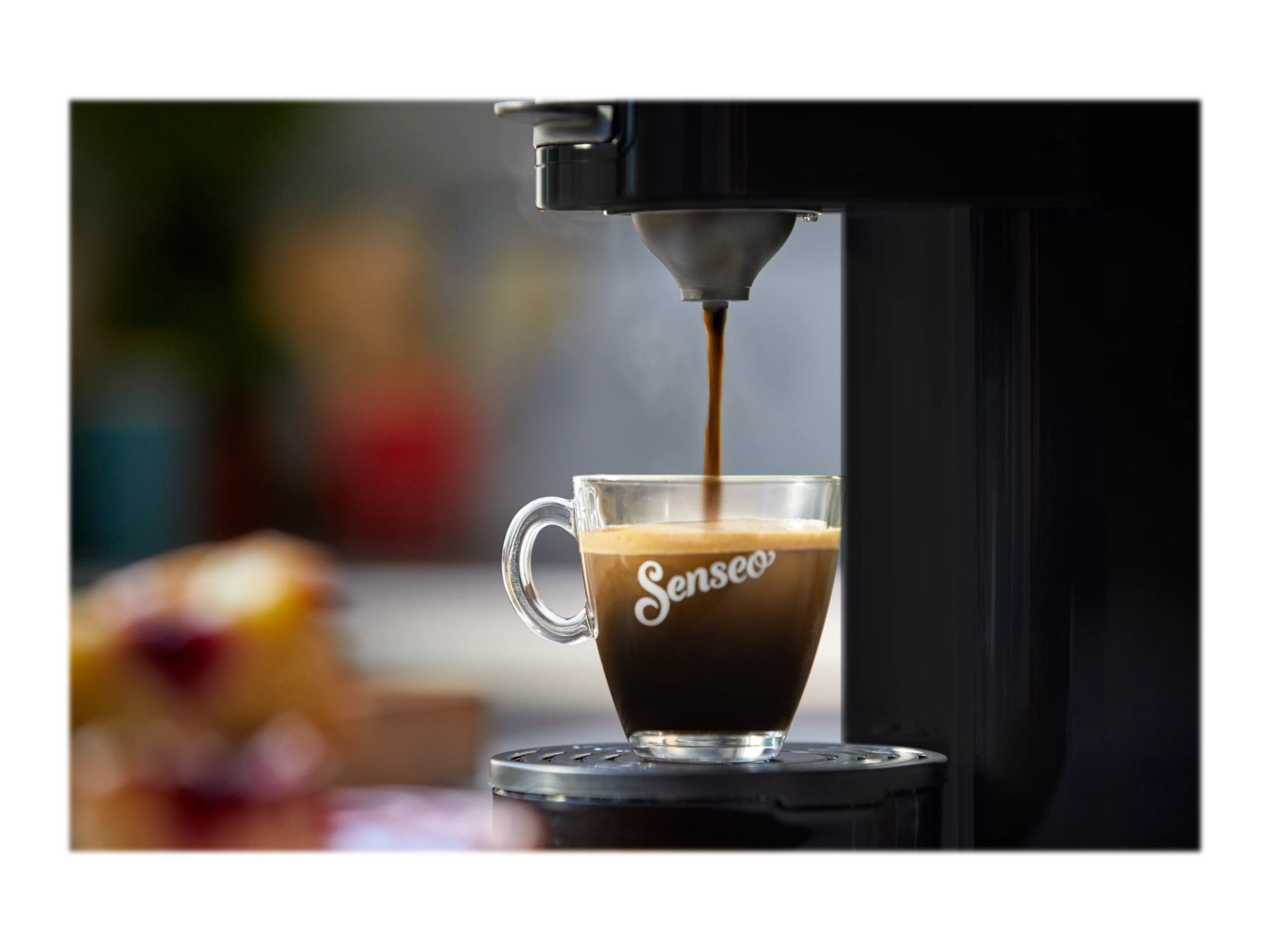 Kaffeemaschine gießt Kaffee in eine Glastasse. Die Tasse hat das Wort Senso darauf.