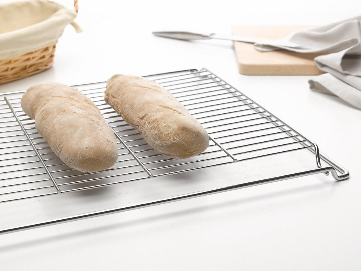 Zwei gebackene Baguettes auf einem Drahtgestell, mit weißem Hintergrund.