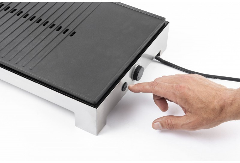 Hand presses a button on a black and steel grill.