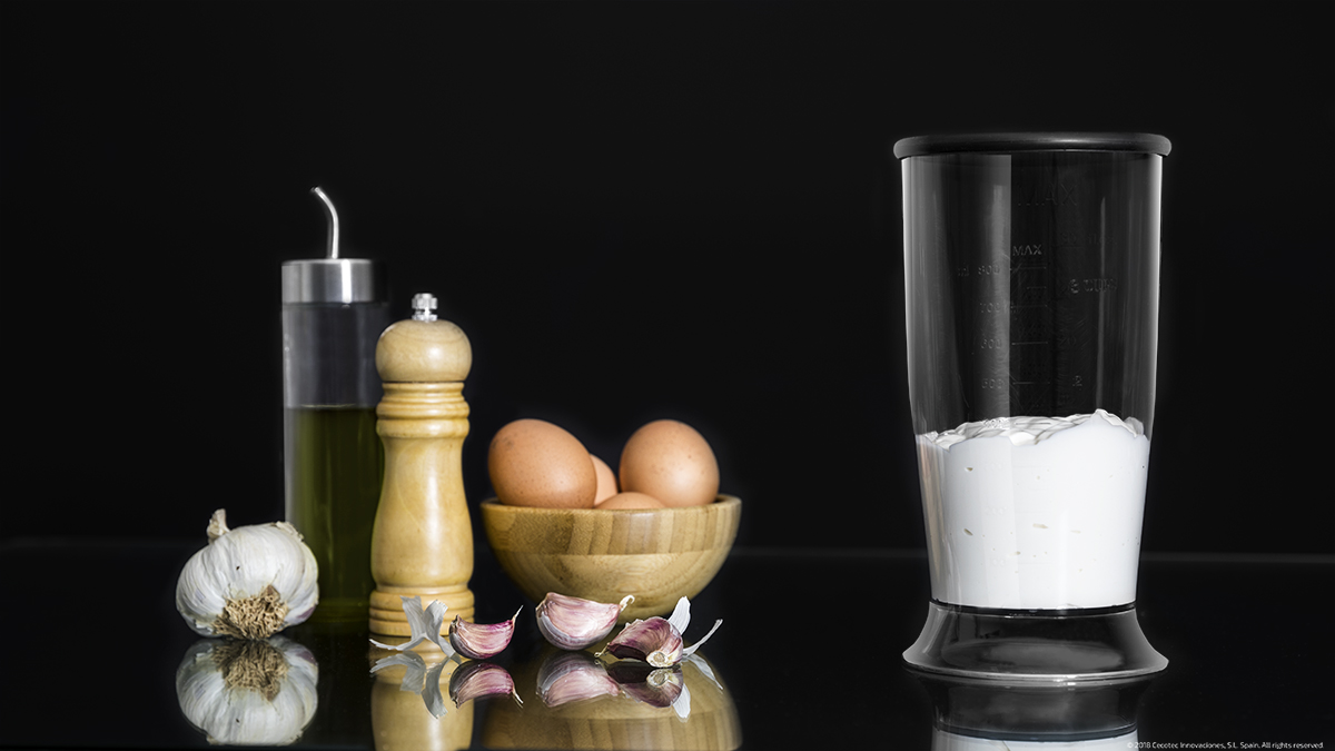 Ingredientes para mayonesa: aceite, molinillo de pimienta, huevos, ajo y una batidora con mezcla blanca.