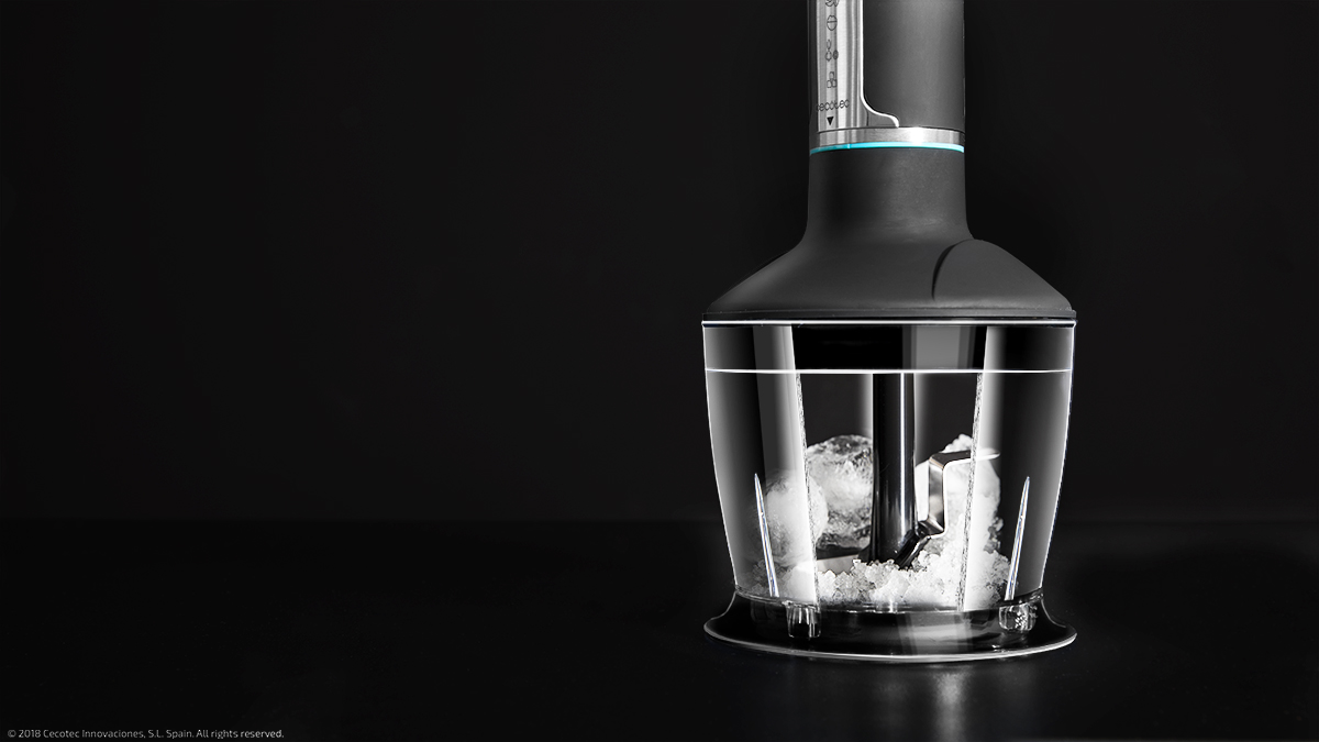 Batidora de inmersión negra, con cubitos de hielo en un recipiente transparente. Fondo negro.
