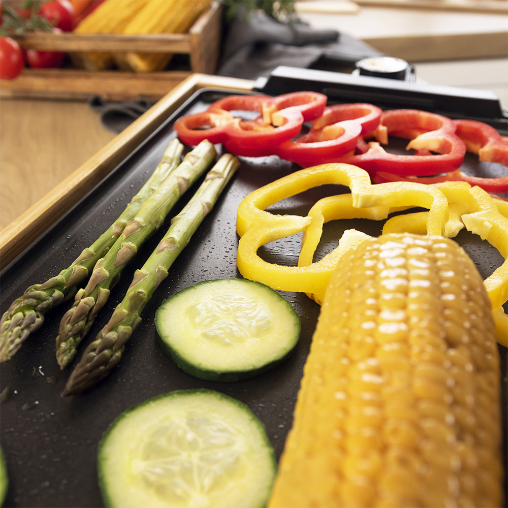 Plancha con espárragos, pimientos en rodajas, pepino y maíz sobre madera.