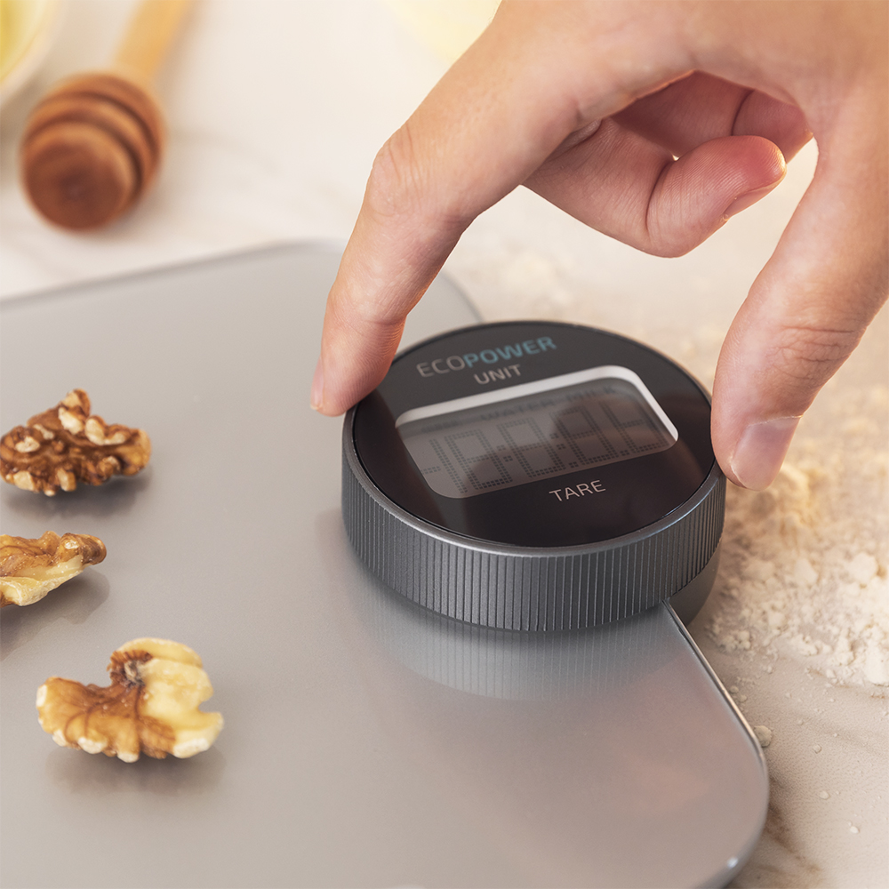 Mano colocando objeto en báscula digital con nueces.