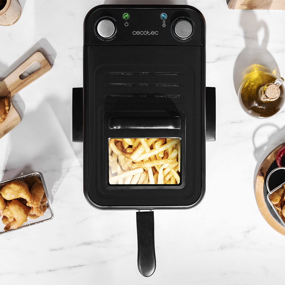 Una freidora de aire con papas fritas dentro, rodeada de otros alimentos.