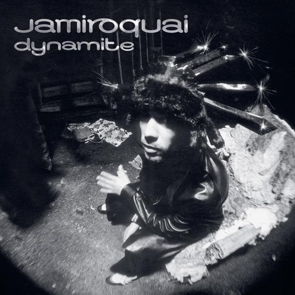 Albumcover von Jamiroquais Dynamite. Ein Mann mit Pelzmütze schaut nach unten. Der Hintergrund ist verschwommen.