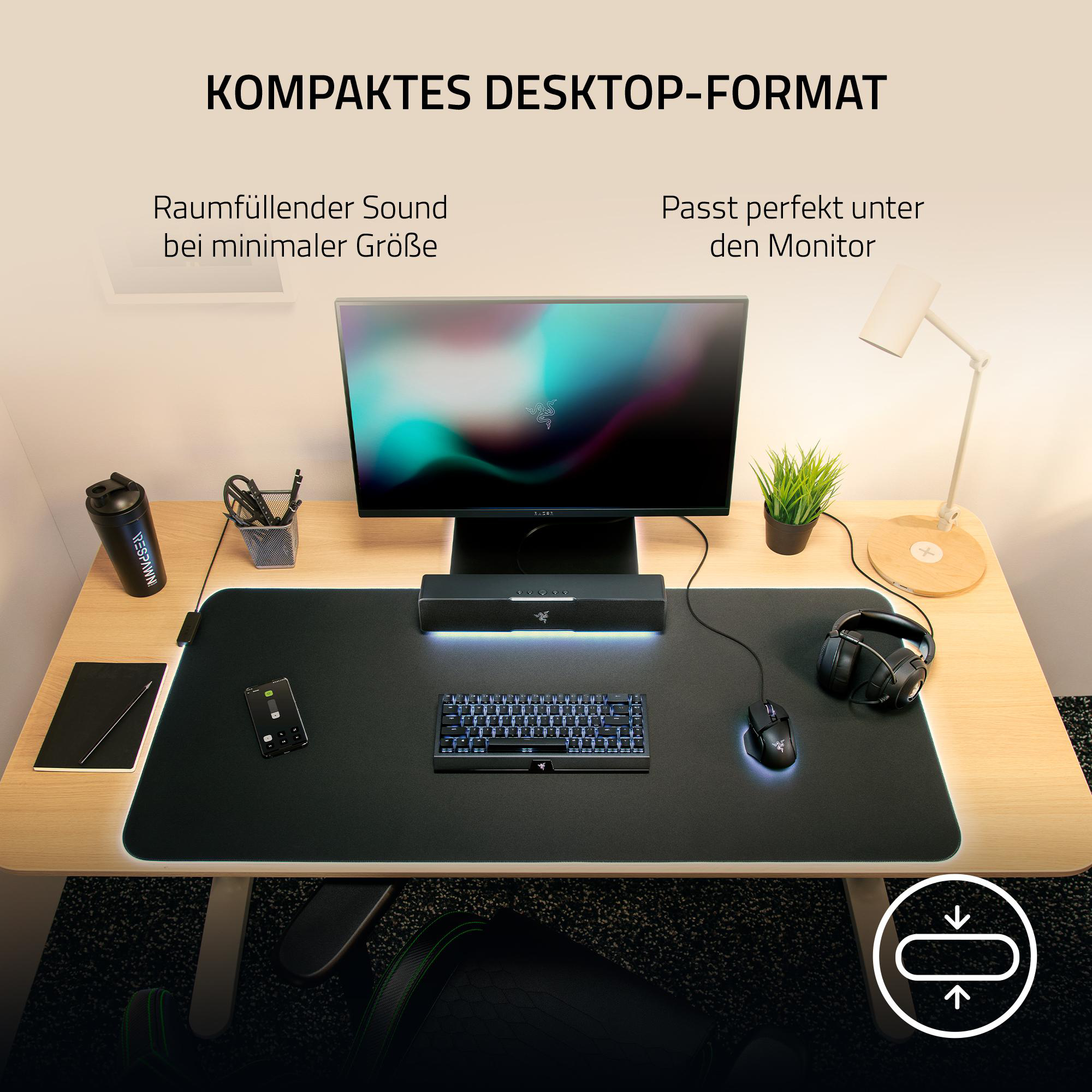 Desktop-Setup mit Monitor, Tastatur, Maus und Soundbar. Inklusive Kopfhörer, Wasserflasche und Pflanze.