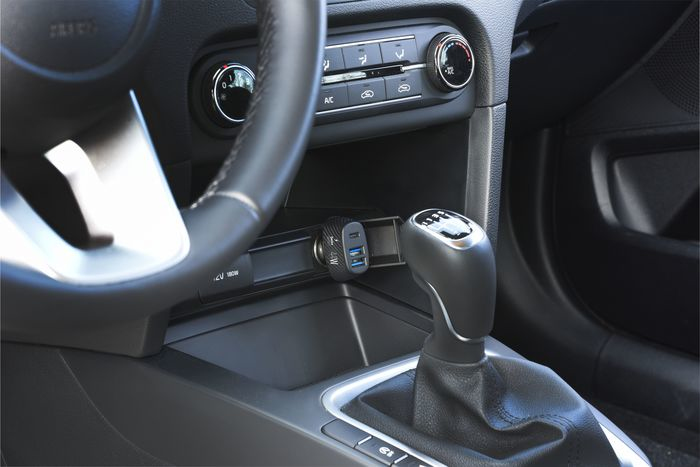 Vista interior del coche. Palanca de cambios, volante y consola con puertos USB y controles climáticos visibles.