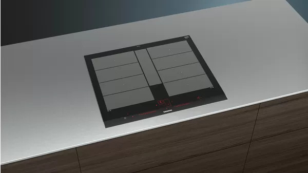 A modern black induction cooktop built into a light-colored countertop. The surface is stainless steel.