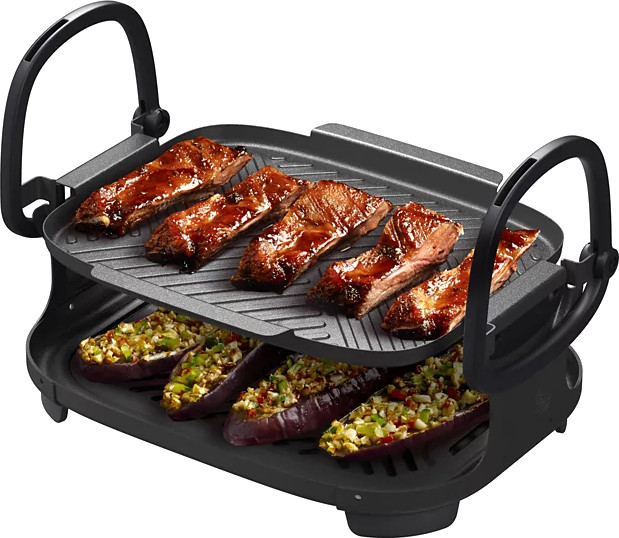 Electric grill with cooked ribs and stuffed eggplants. Black grill with food on it.