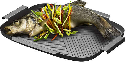 A cooked fish on a grill pan, garnished with colorful vegetables, ready to serve.