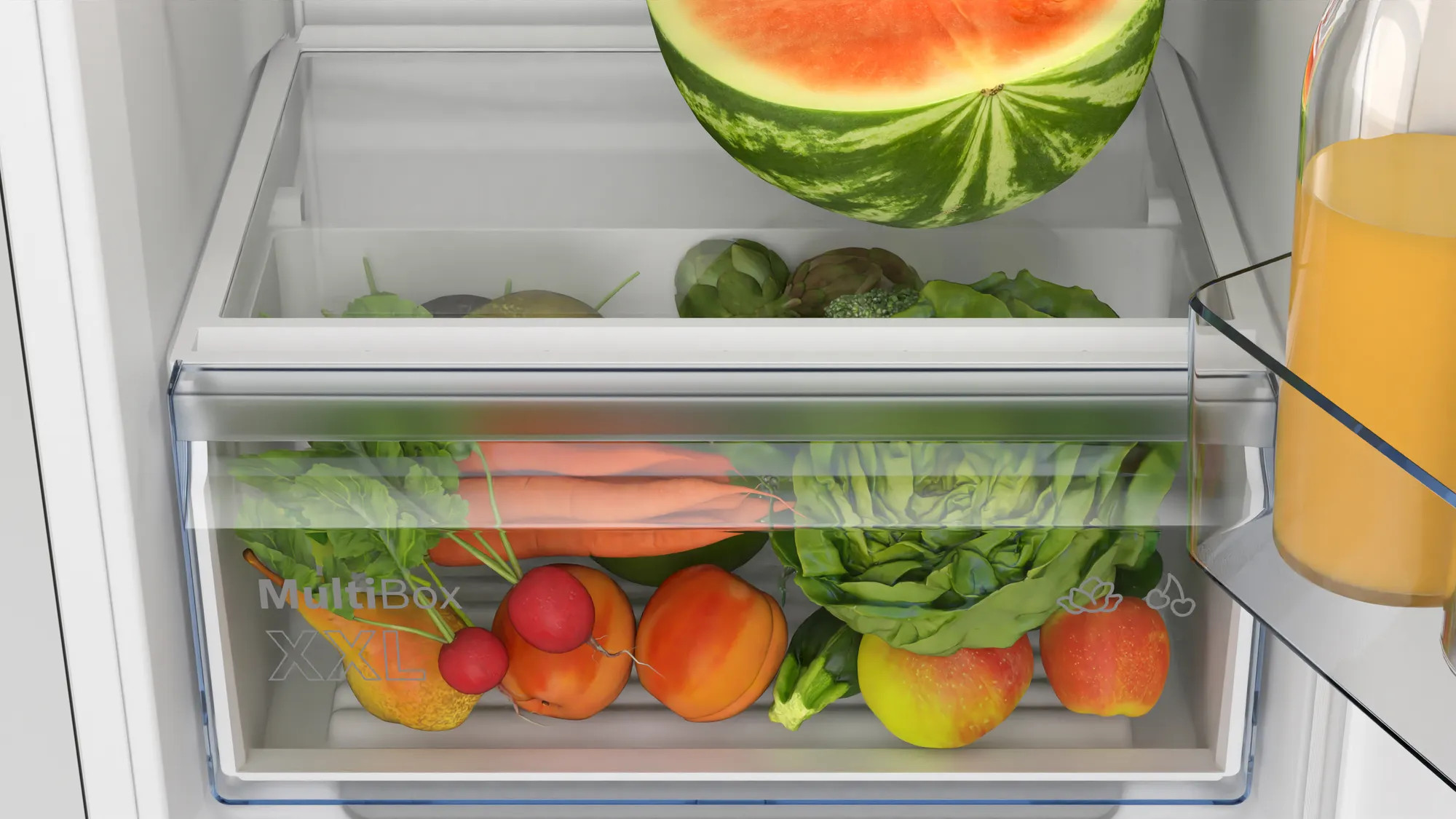 In een koelkast, een heldere lade met diverse groenten en fruit, waaronder wortelen, appels en radijsjes.
