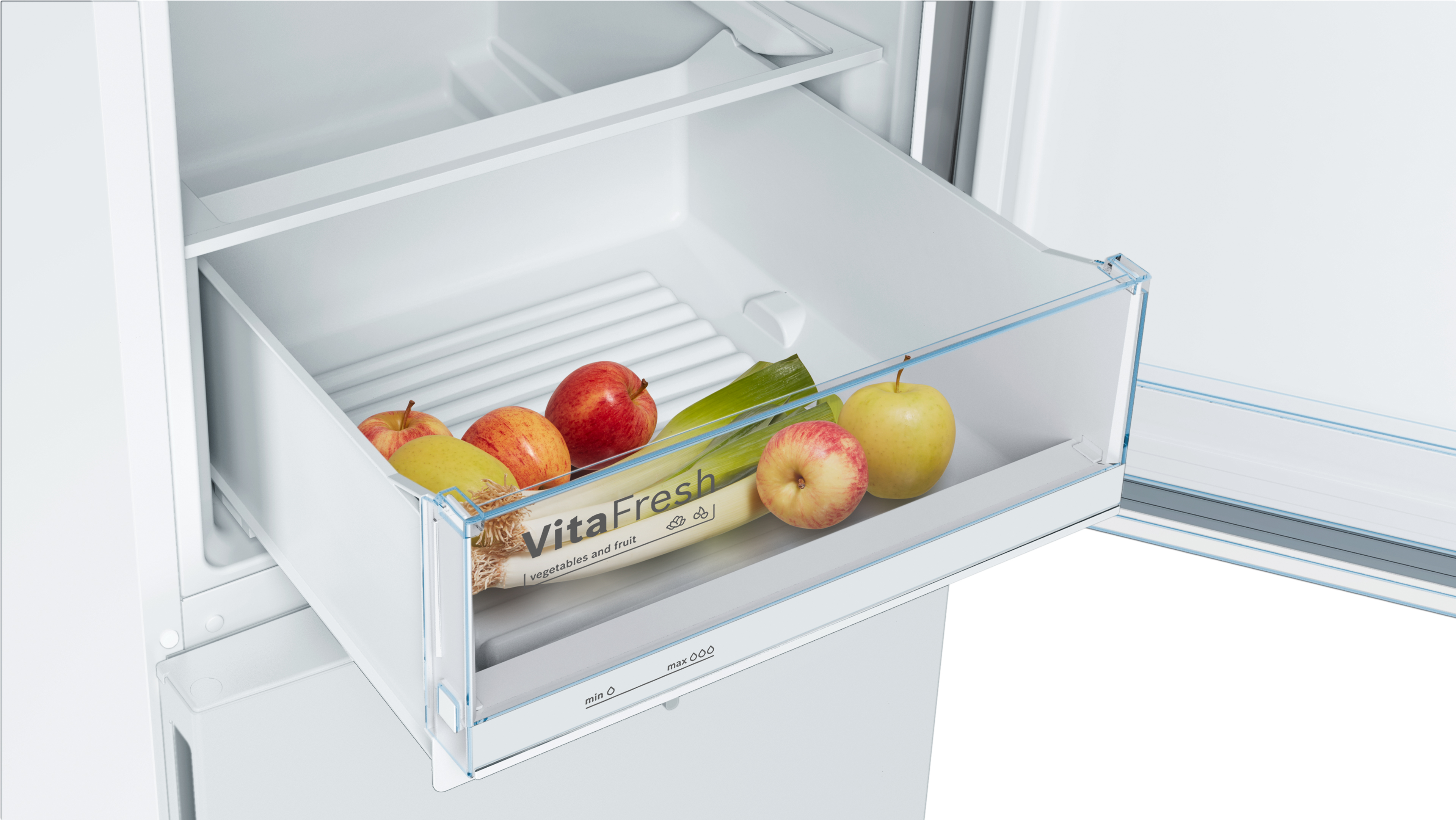 A refrigerator drawer with fruits and vegetables. Apples, leeks, and a 'VitaFresh' label are visible.