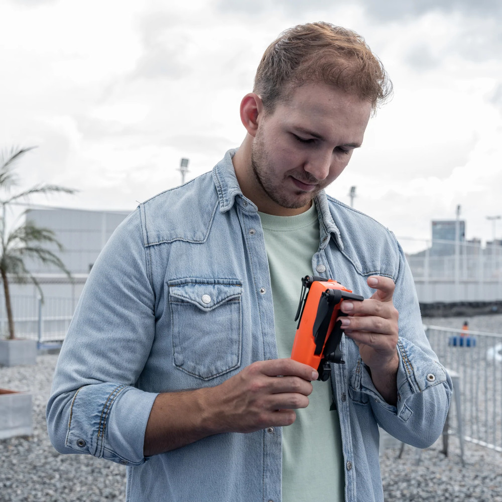 Een man die een oranje drone vasthoudt.