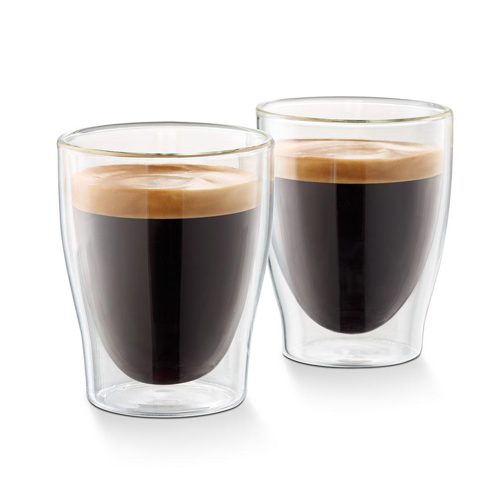 Zwei klare Gläser mit dunklem Kaffee und einer Schaumschicht, auf weißer Oberfläche.