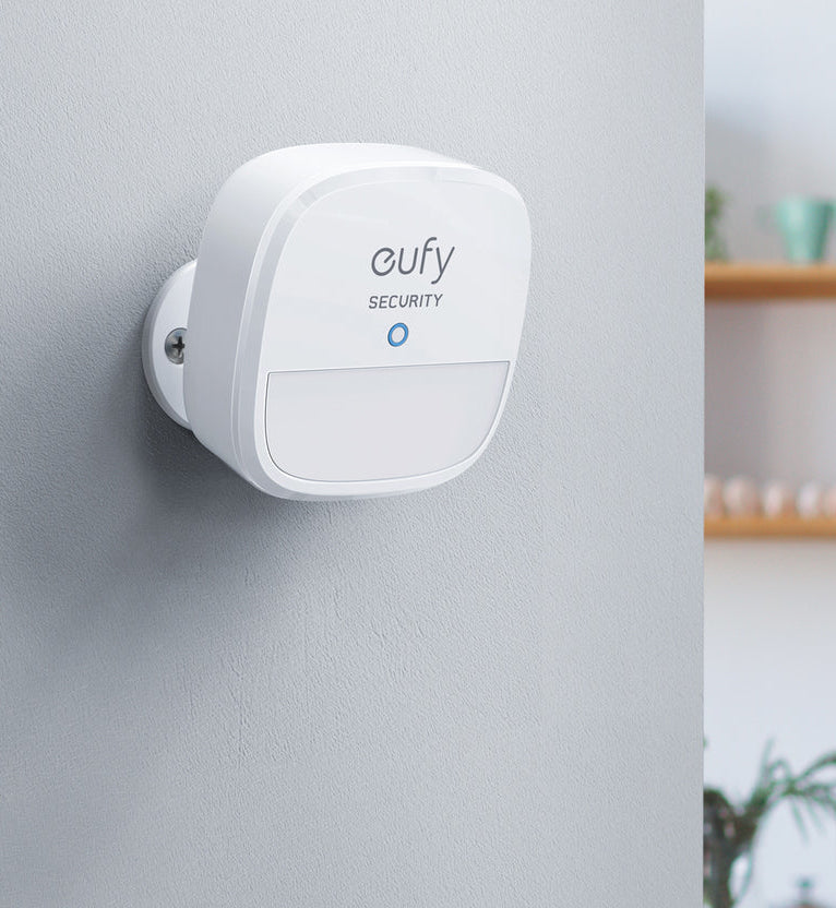 Witte beveiligingscamera gemonteerd op een grijze muur. Met het 'eufy SECURITY' logo.