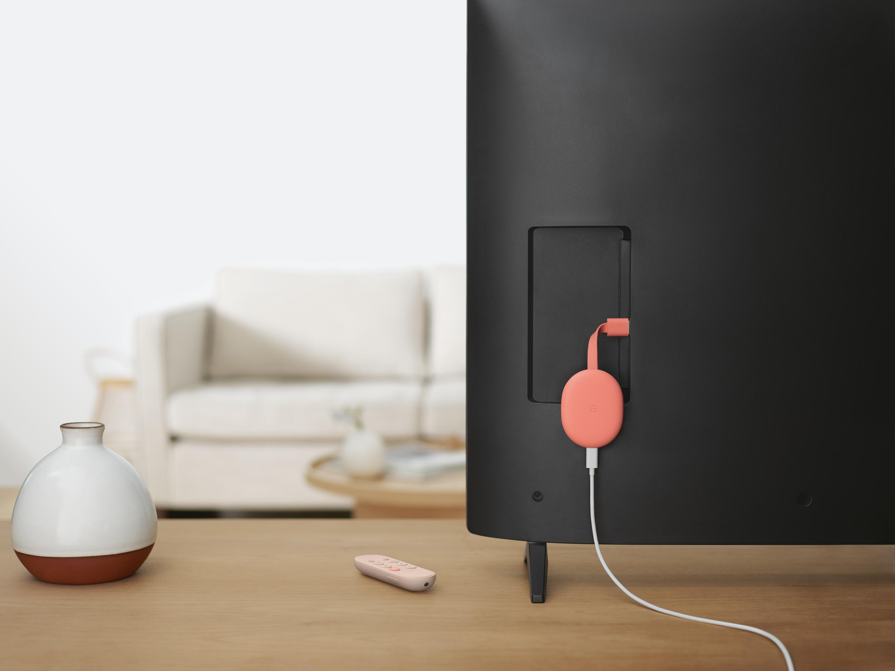Parte trasera de un televisor con un Google Chromecast rosa conectado y un mando.