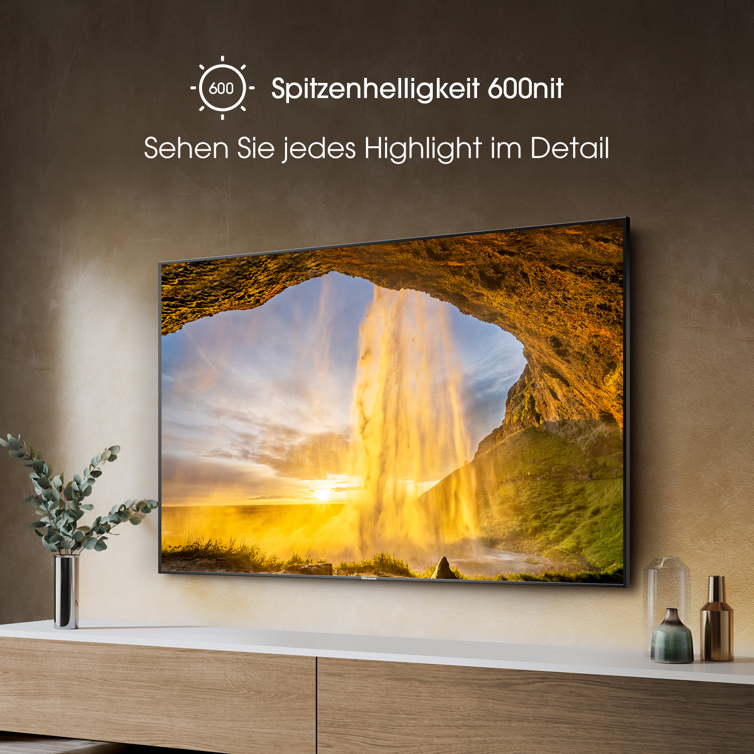 Großer TV-Bildschirm mit Wasserfallszene, darunter ein Holzschrank. Dunkler Raum.