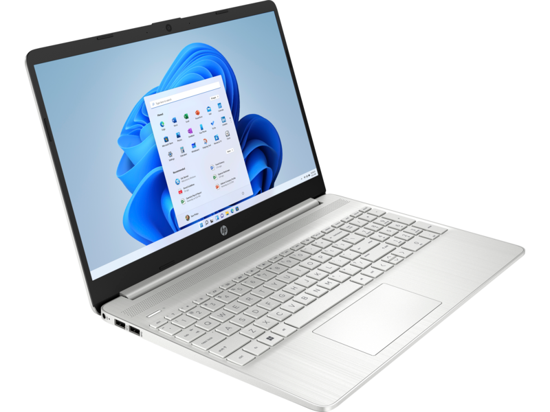 Portátil plateado abierto, mostrando interfaz de Windows 11 sobre superficie blanca.