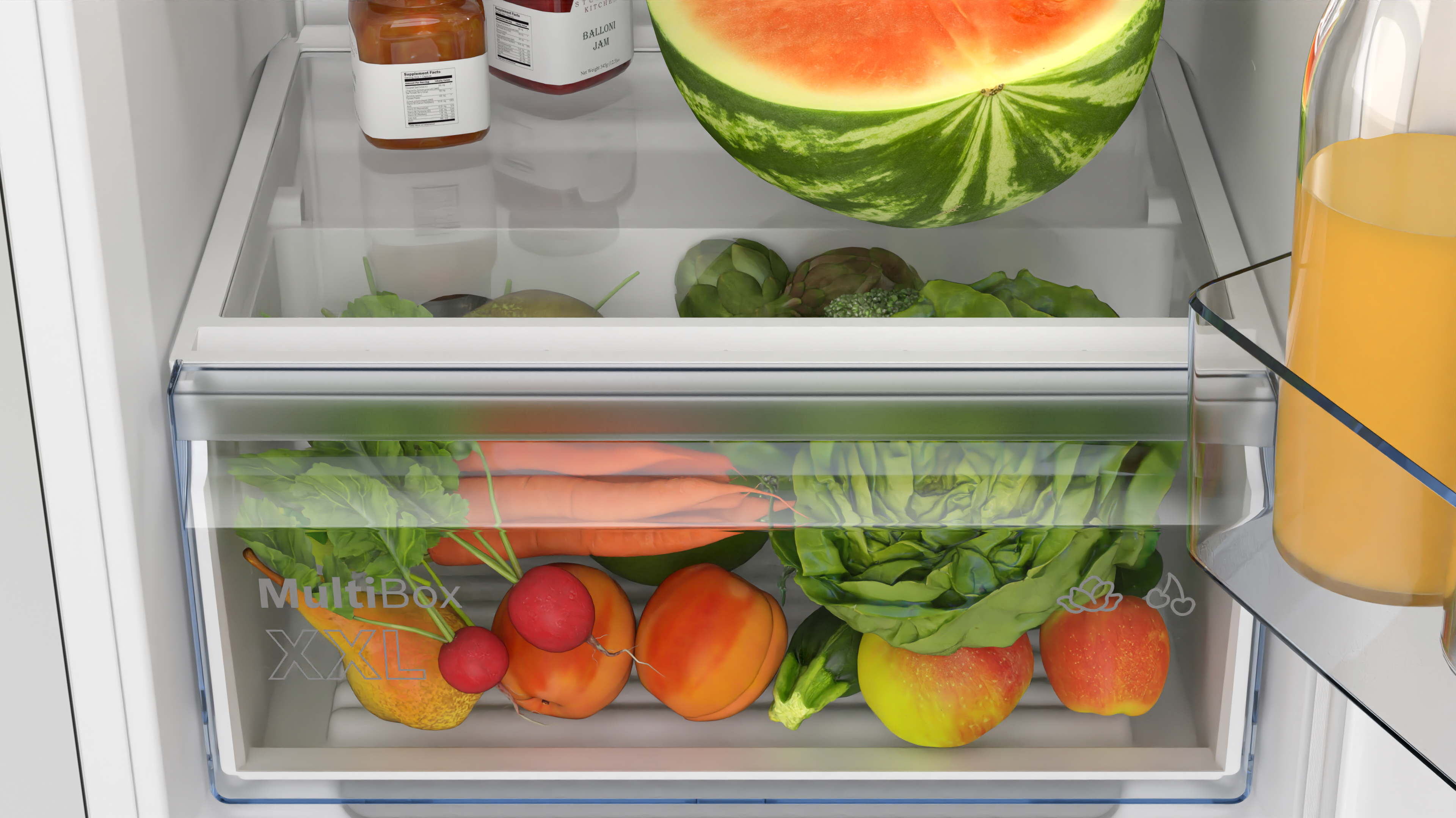Refrigerator drawer contains fresh produce: carrots, apples, lettuce, watermelon.