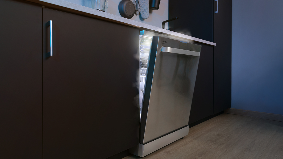 Un lavavajillas con la puerta abierta, emitiendo vapor en una cocina moderna.
